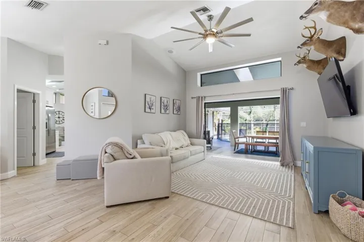 Living area with a ceiling fan, light wood-style flooring, and lofted ceiling