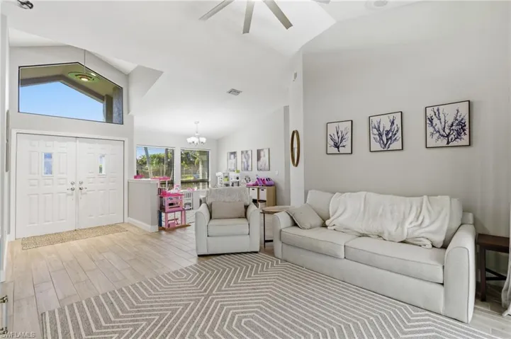 Living area featuring vaulted ceiling, wood tiled floors, suspended lighting, and ceiling fan
