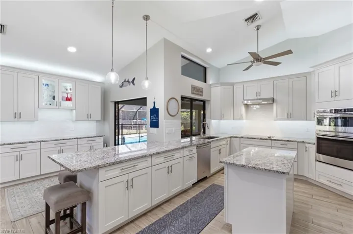 Kitchen featuring tasteful backsplash, lofted ceiling, a kitchen island, and white cabinets