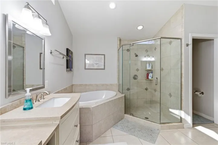 Full bath featuring a bath, vanity, light tile patterned flooring, a shower stall, and recessed lighting