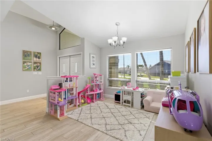 Recreation room featuring hanging lights, light wood finished floors, and vaulted ceiling