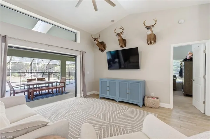 Living room with vaulted ceiling, ceiling fan, light wood-style floors, healthy amount of natural light, and a sunroom