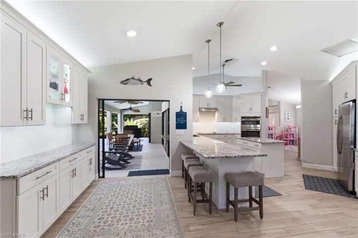 Kitchen featuring white cabinetry, ceiling fan, backsplash, a peninsula, and light stone countertops
