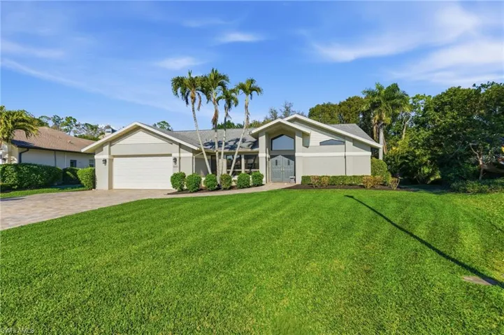Mid-century inspired home featuring a front yard, an attached garage, driveway, and stucco siding