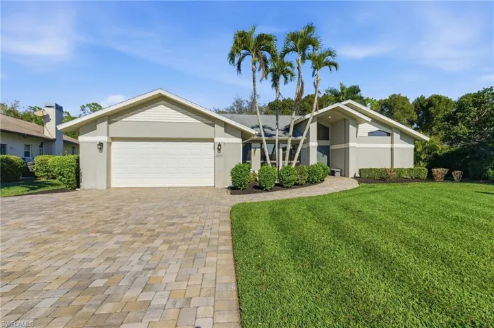 Mid-century inspired home with a front lawn, a garage, stucco siding, and driveway