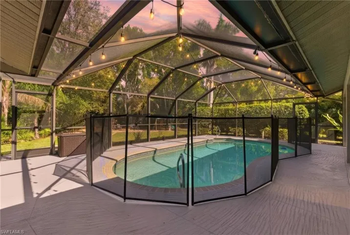 View of swimming pool with glass enclosure, patio surround, and a sunroom