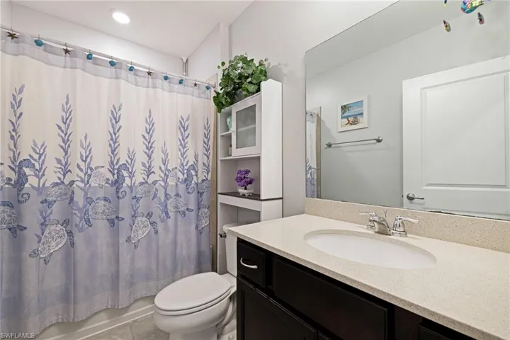 Bathroom with vanity, shower / bath combo, and light tile patterned flooring