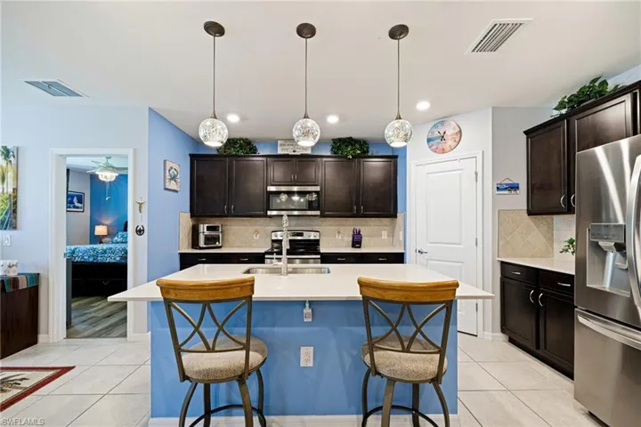 Kitchen featuring stainless steel appliances, dark wood finish cabinetry, and light tile patterned floors