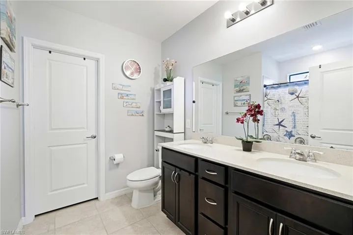 Bathroom featuring double vanity, a shower stall, and light tile patterned flooring