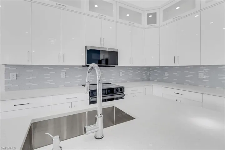 Kitchen featuring appliances with stainless steel finishes, tasteful backsplash, and white cabinets