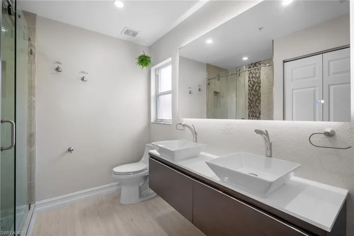 Full bathroom with double vanity, light wood finished floors, a shower stall, and recessed lighting