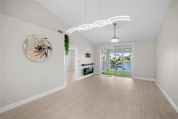 Unfurnished living room featuring light wood-style floors, a water view, and lofted ceiling