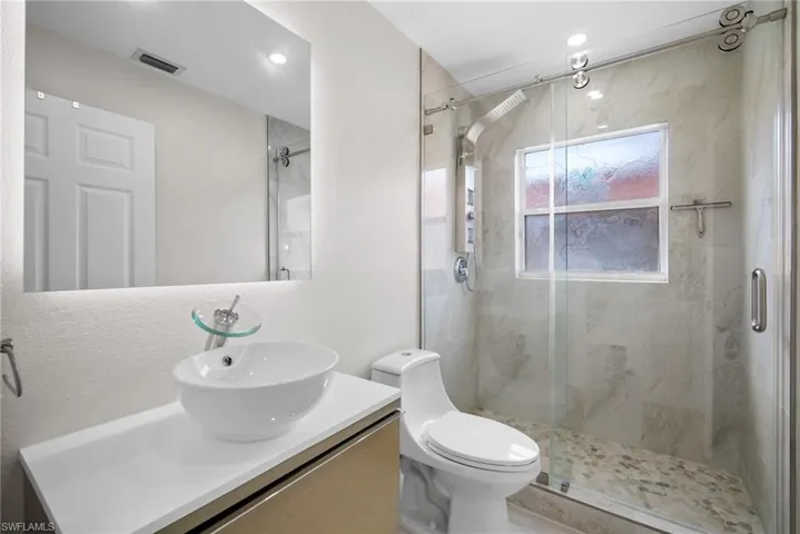 Bathroom featuring vanity and a marble finish shower