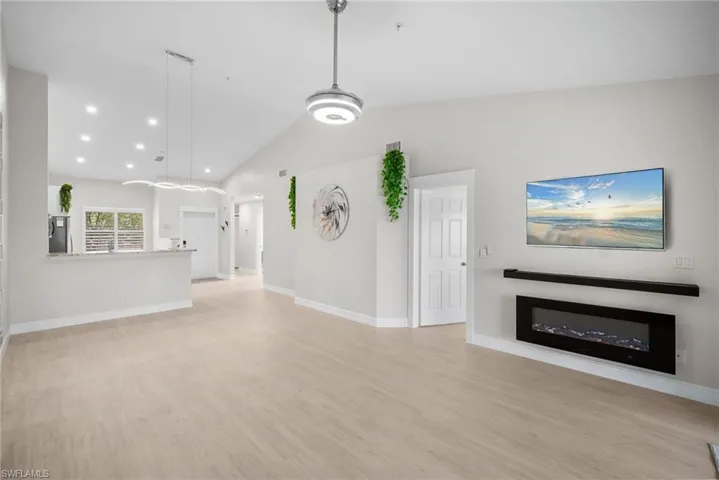 Unfurnished living room featuring vaulted ceiling, light wood-style flooring, recessed lighting, and a fireplace