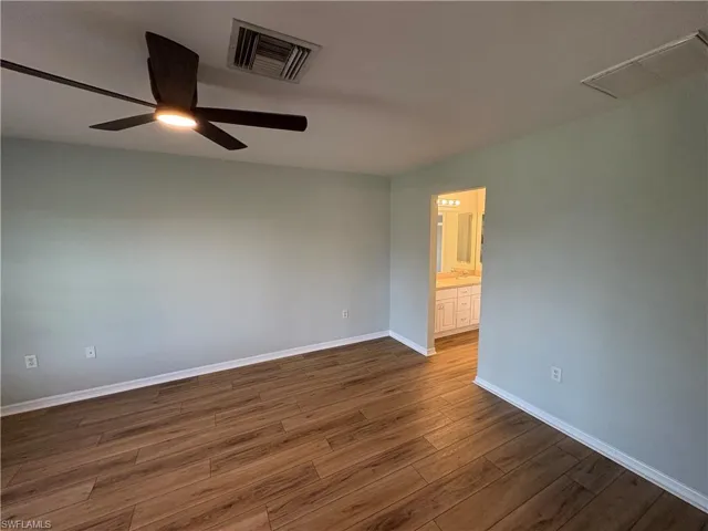 Unfurnished room with dark wood-style floors and ceiling fan