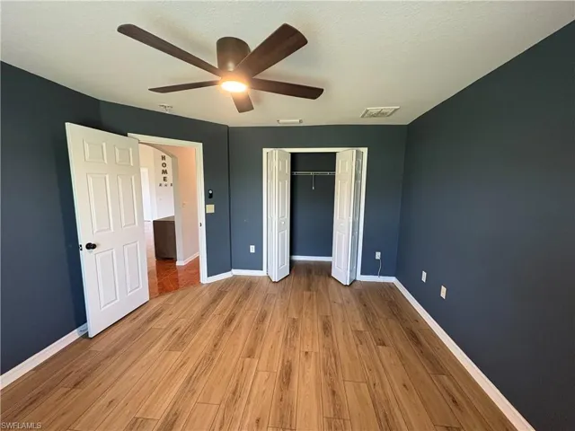 Unfurnished bedroom featuring light wood-type flooring, a ceiling fan, a closet, and a textured ceiling