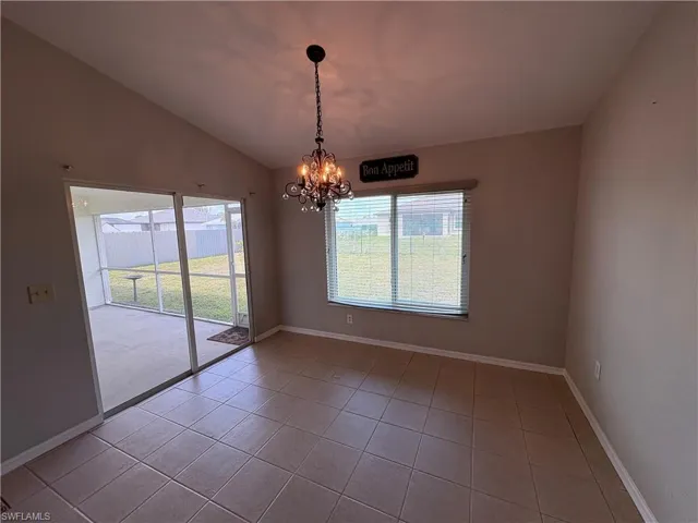 Unfurnished dining area with a chandelier, light tile patterned flooring, and vaulted ceiling