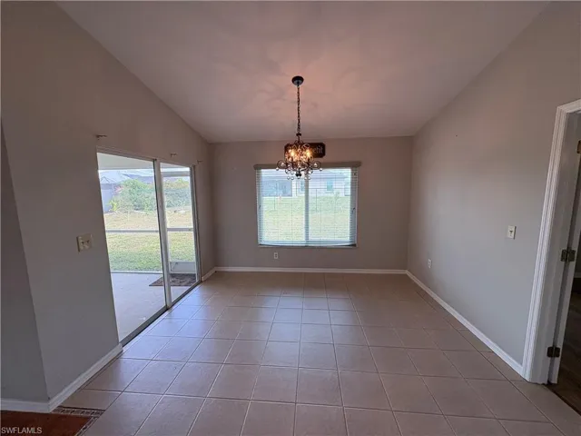 Unfurnished dining area featuring a chandelier, lofted ceiling, and light tile patterned flooring