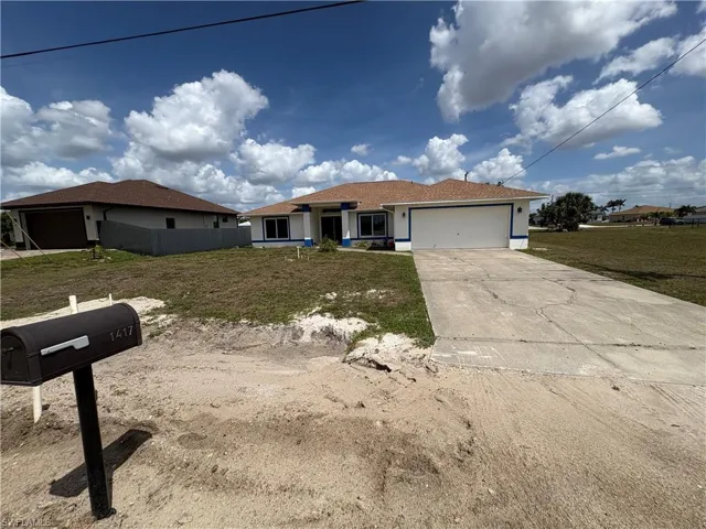 Ranch-style home featuring driveway, a garage, a front lawn, and stucco siding