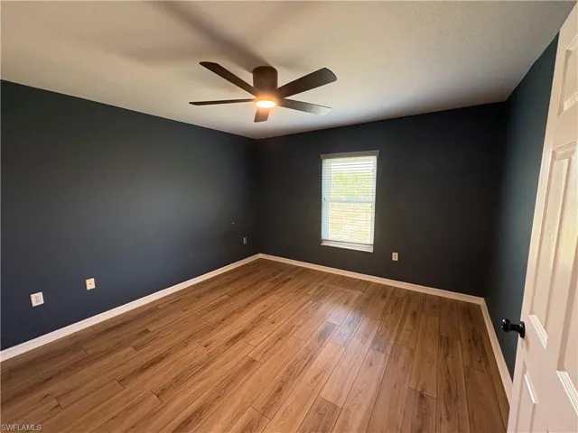 Empty room with light wood finished floors, a textured ceiling, and a ceiling fan