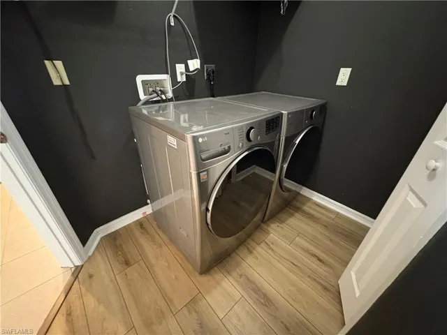 Washroom with light wood-style floors and washing machine and dryer