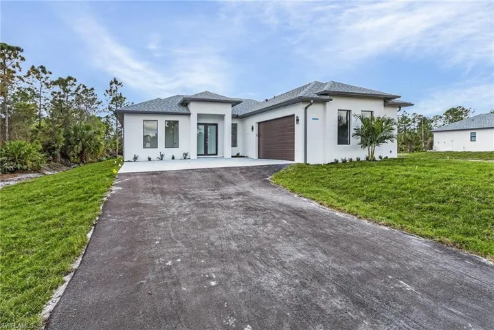Prairie-style house with a front lawn, asphalt driveway, stucco siding, and an attached garage