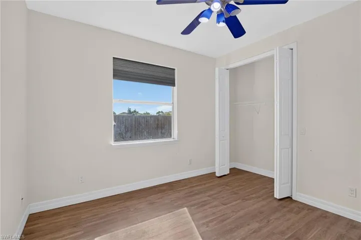Wood-finish flooring, ceiling fan with integrated lighting, window with exterior roller shutter, and bifold closet doors