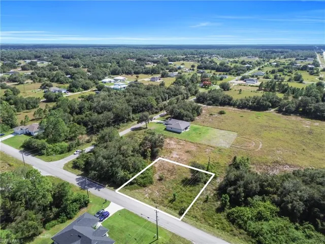 Aerial view of residential area featuring property parcel outlined and a forest
