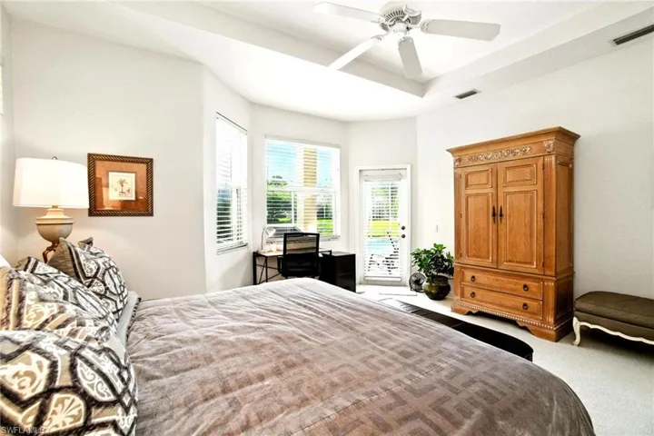 Carpeted bedroom featuring access to exterior, a raised ceiling, and ceiling fan