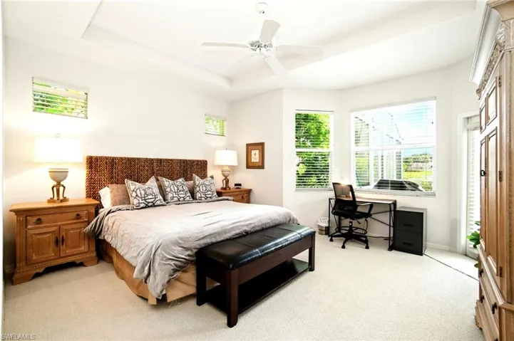 Bedroom with a raised ceiling, light carpet, access to exterior, and ceiling fan