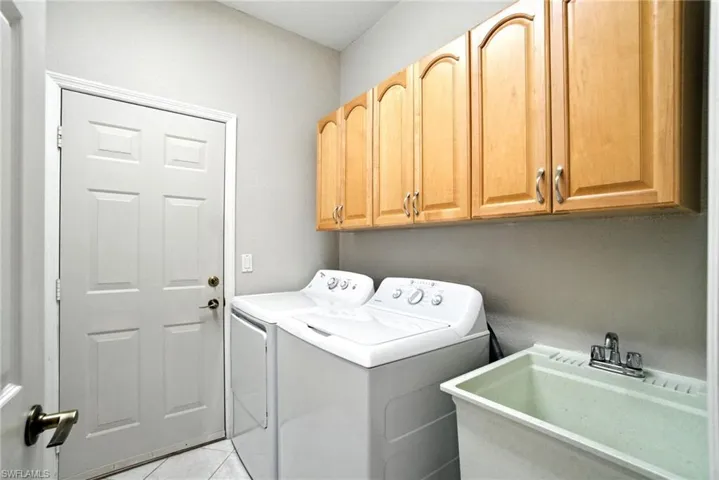 Laundry area with independent washer and dryer, cabinet space, and light tile patterned floors
