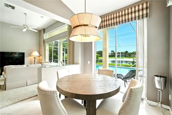 Dining room featuring light tile patterned floors, a ceiling fan, a water view, and a sunroom