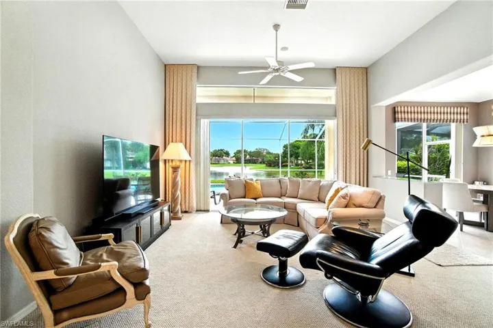 Living area with ceiling fan, carpet flooring, and a sunroom