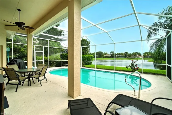 Outdoor pool featuring a sunroom, glass enclosure, a patio, a water view, and grilling area