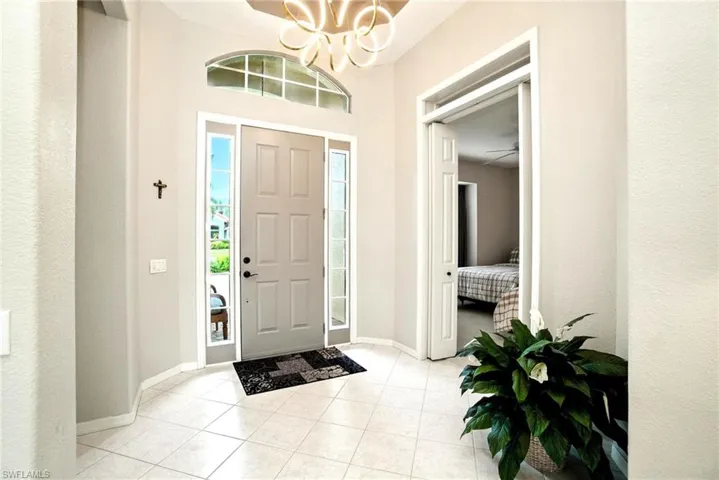 Foyer featuring light tile patterned floors, a chandelier, and ceiling fan
