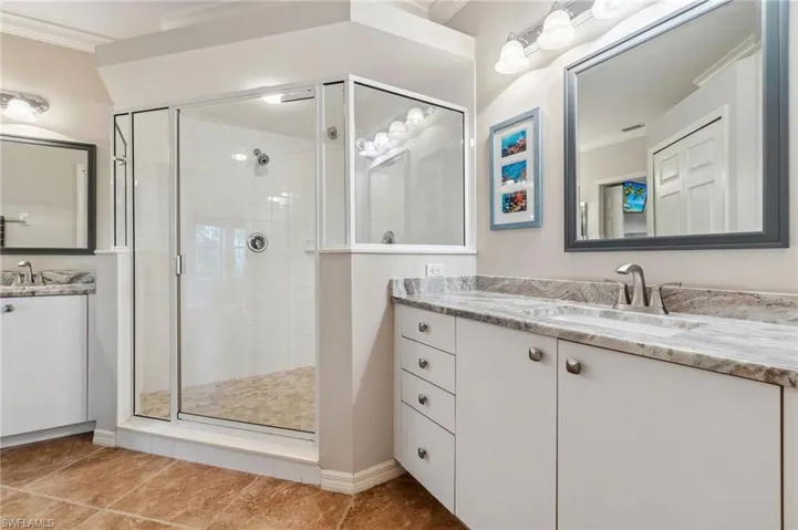 Bathroom with tile patterned flooring, a stall shower, two vanities, a sink, and ornamental molding