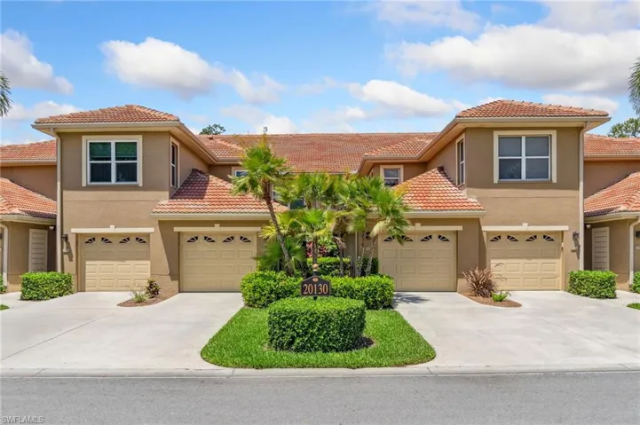 View of front of home with stucco siding, driveway, and a tile roof