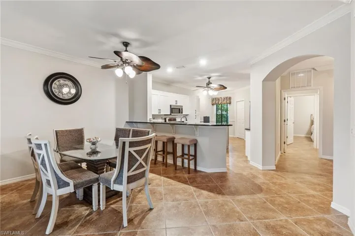 Dining room featuring ornamental molding, ceiling fan, light tile patterned floors, and arched walkways