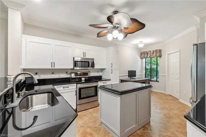 Kitchen featuring a sink, a center island, stainless steel appliances, backsplash, and ornamental molding