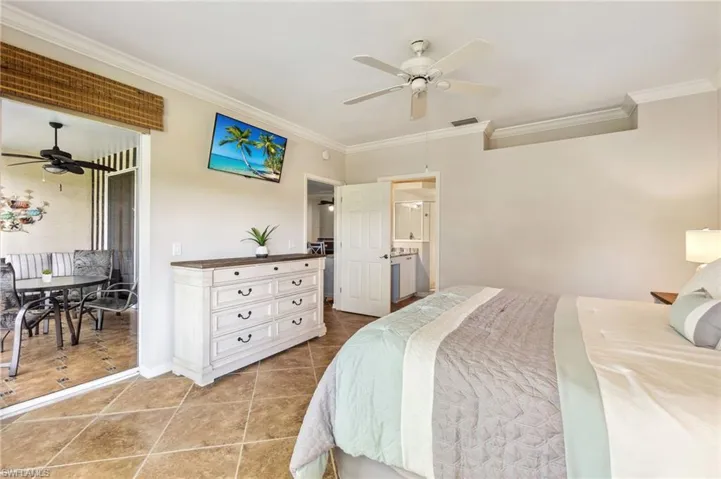 Bedroom featuring ceiling fan, visible vents, light tile patterned floors, baseboards, and ornamental molding