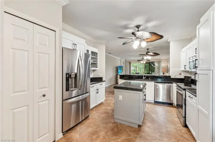 Kitchen featuring crown molding, ceiling fan, white cabinetry, a sink, and appliances with stainless steel finishes
