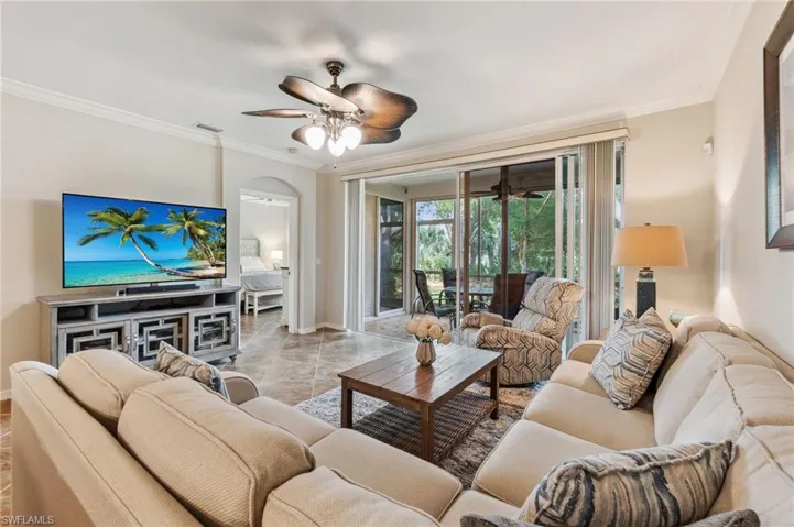 Living area with baseboards, ornamental molding, arched walkways, and ceiling fan