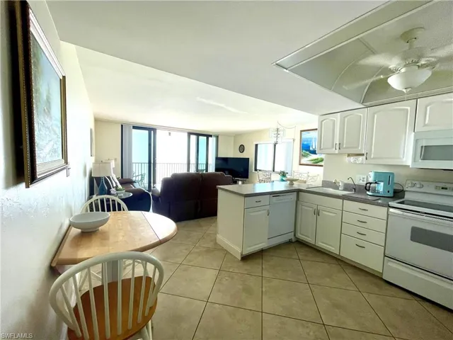 Kitchen featuring white appliances, white cabinets, open floor plan, a peninsula