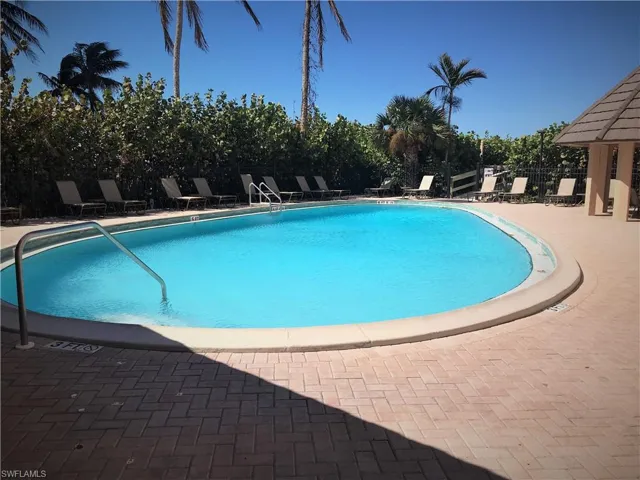 Sea Winds Community pool featuring a patio area with chaise lounge chairs with access to beach