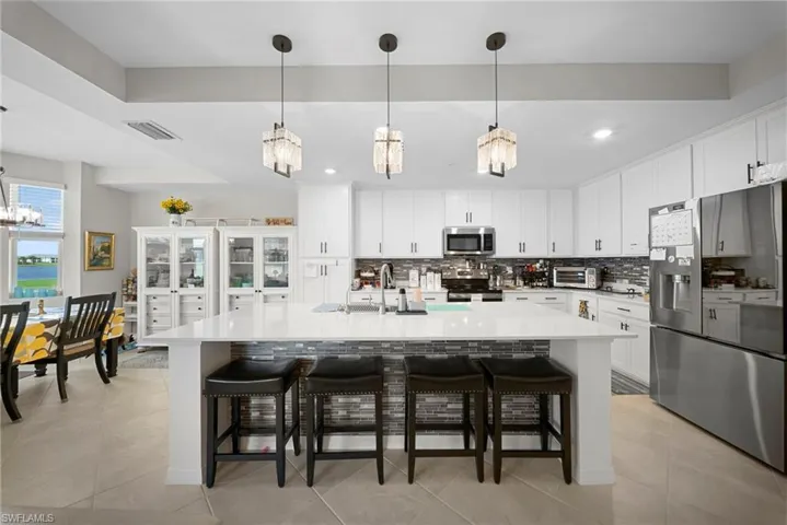 Kitchen featuring stainless steel appliances, white cabinets, a large island, and a breakfast bar area