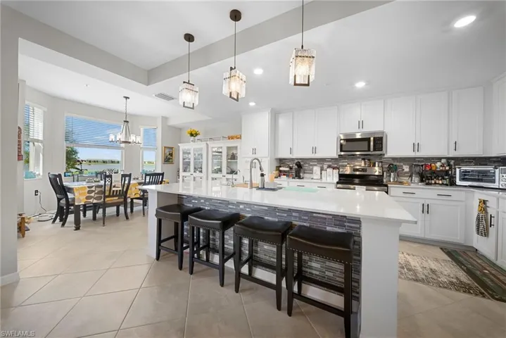 Kitchen featuring a breakfast bar, white cabinetry, a kitchen island with sink, and stainless steel appliances