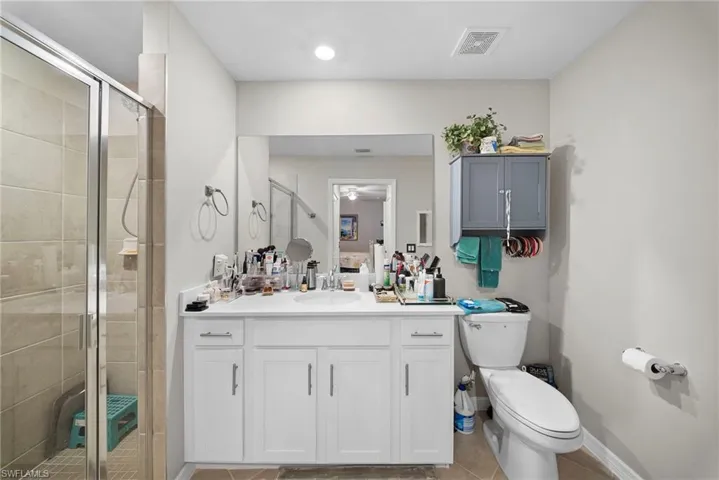 Ensuite bathroom featuring a stall shower, vanity, and light tile patterned floors