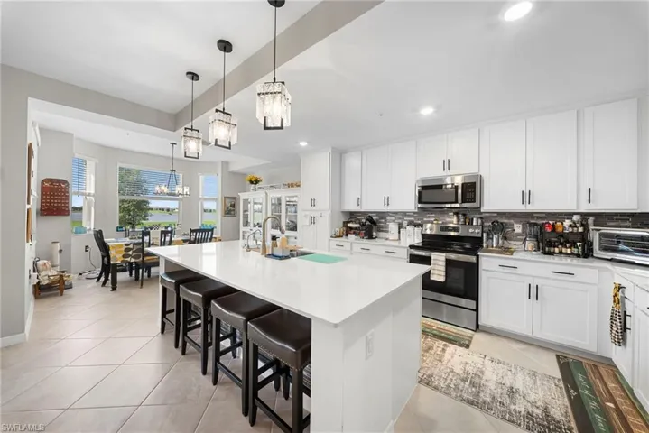 Kitchen with a center island with sink, stainless steel appliances, a breakfast bar area, and white cabinets