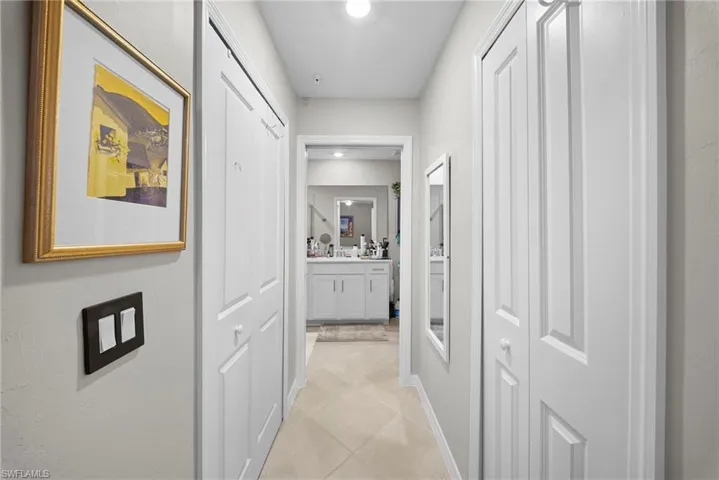 Corridor with light tile patterned flooring and baseboards