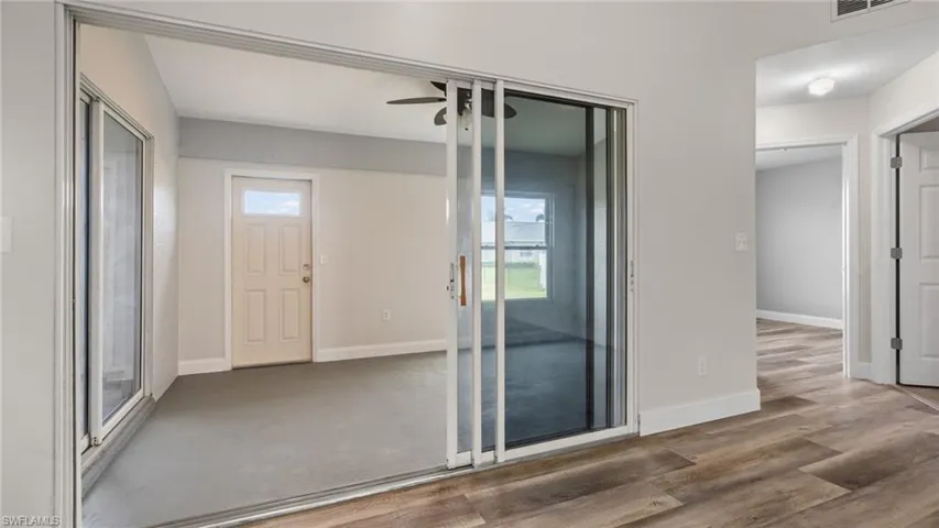 Unfurnished room featuring dark wood-type flooring, ceiling fan, and a healthy amount of sunlight